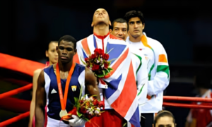 Three Olympic medalists standing on the podium, draped in their country’s flags